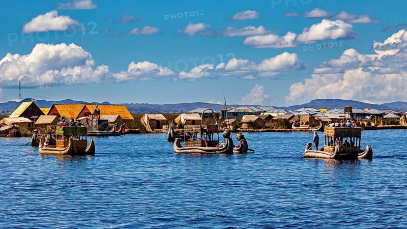 Several boats near a collection of reed huts on the lake, The floating reed islands of the Uros in Lake Titicaca in Peru