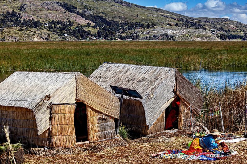 Reed huts with colorful ceilings at the lake in quiet surroundings, The floating reed islands of Uros in Lake Titicaca in Peru