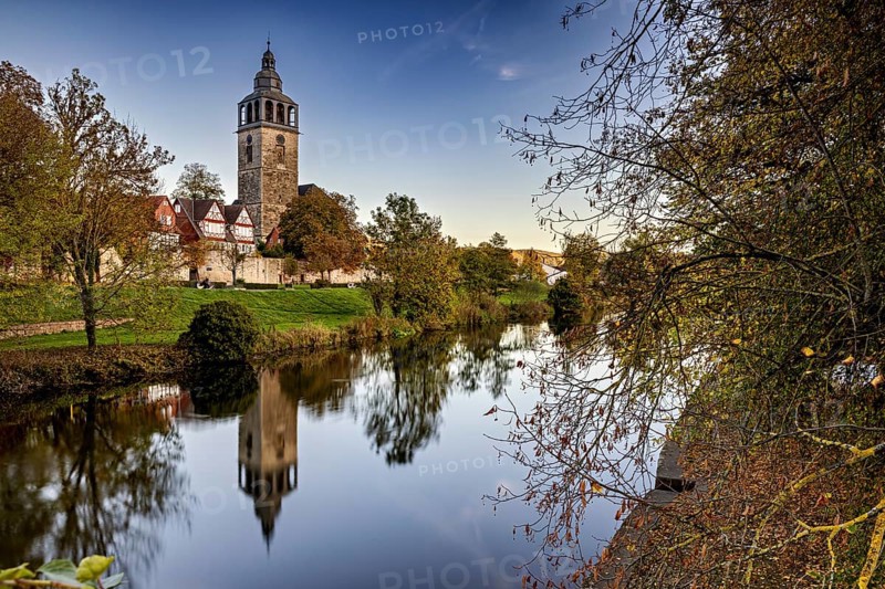 Church on the river, surrounded by autumnal trees with beautiful reflections in calm water, The town of Bad Sooden Allendorf an der Werra in the Werra Meissner district of Hesse