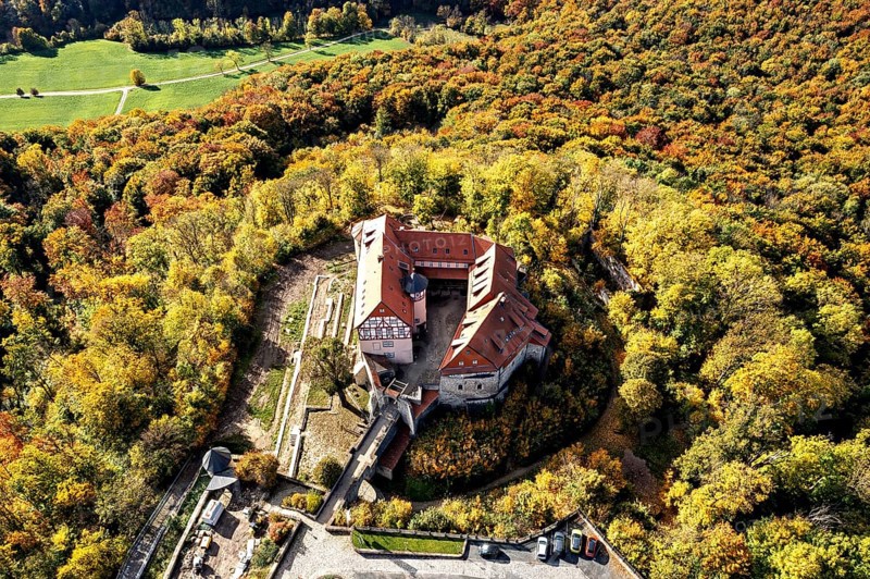 Castle nestled in colorful autumn landscape, surrounded by lush forest, seen from the air, Bodenstein Castle in the Eichsfeld district of Thuringia