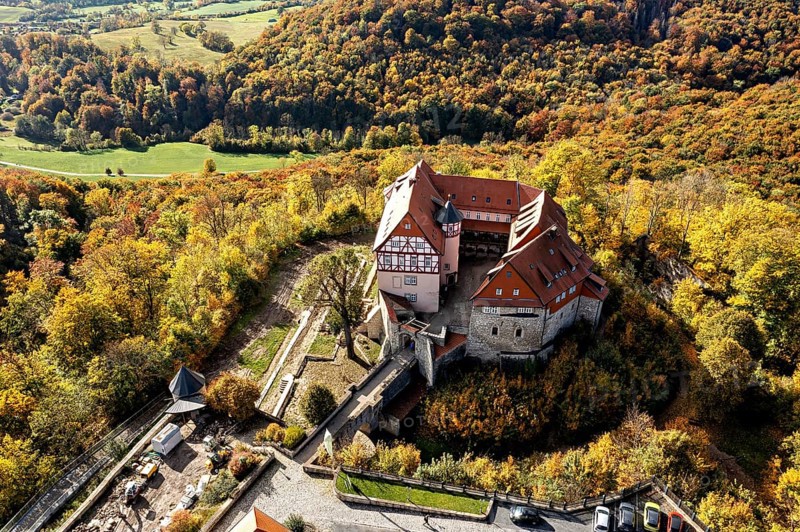 Historic castle perched over colorful autumn forest, landscape viewed from the air, Bodenstein Castle in the Eichsfeld district of Thuringia
