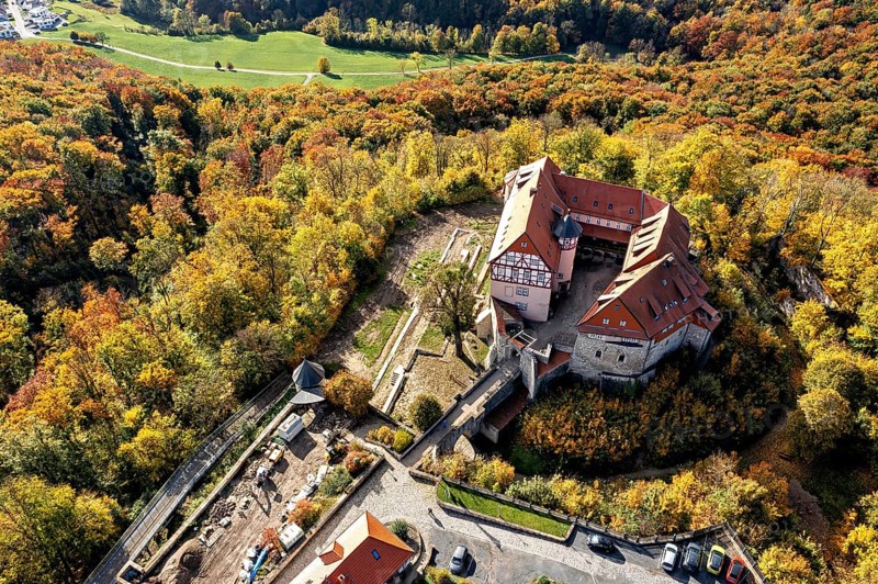 Castle with red tiled roofs, surrounded by autumn-coloured forest landscape, from a bird's eye view, Bodenstein Castle in the Eichsfeld district of Thuringia