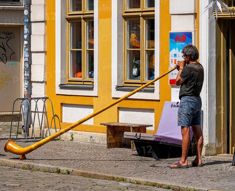 Man with an alphorn in front of the music store in Gutenbergstraße, Potsdam, Brandenburg, Germany
