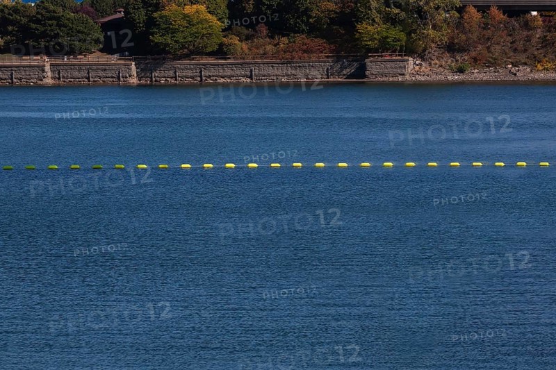 String of yellow cautionary navigation marker buoys on water surafce of river serving to warn, signal or indicate of a hazard beyond, Old Port of Montreal, Quebec, Canada