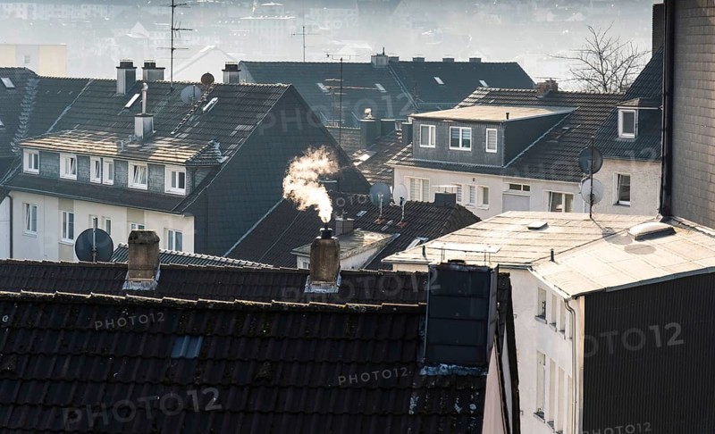 Smoke plume from a chimney over densely built residential area in the evening light, wintry city scene, Wuppertal, Germany