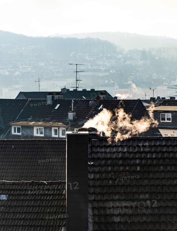 Smoke plume from a chimney over densely built residential area in the evening light, wintry city scene, Wuppertal, Germany
