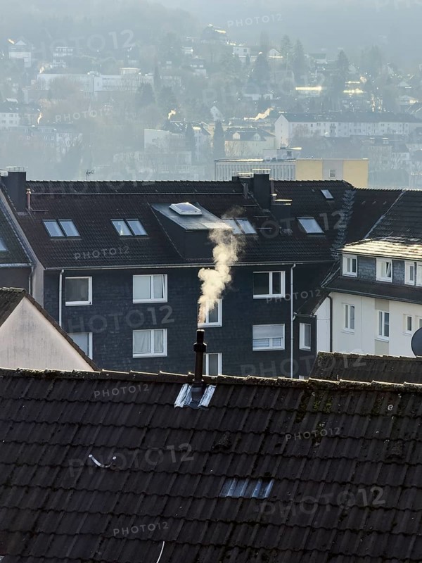 Smoke plume from a chimney over densely built residential area in the evening light, wintry city scene, Wuppertal, Germany