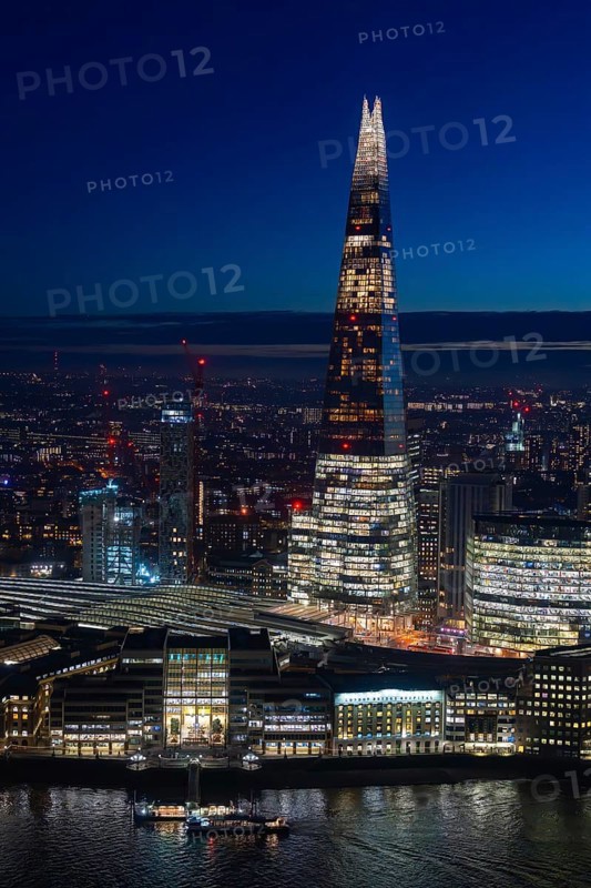 The Shard, pyramid-shaped skyscraper and London Bridge Station along the River Thames in Southwark at night at the capital city London, England, UK