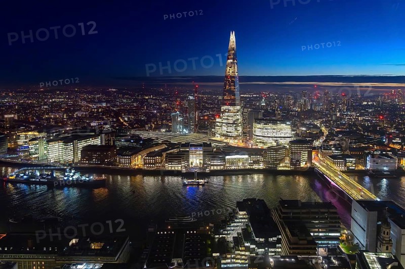 The Shard, pyramid-shaped skyscraper and London Bridge Station along the River Thames in Southwark at night at the capital city London, England, UK