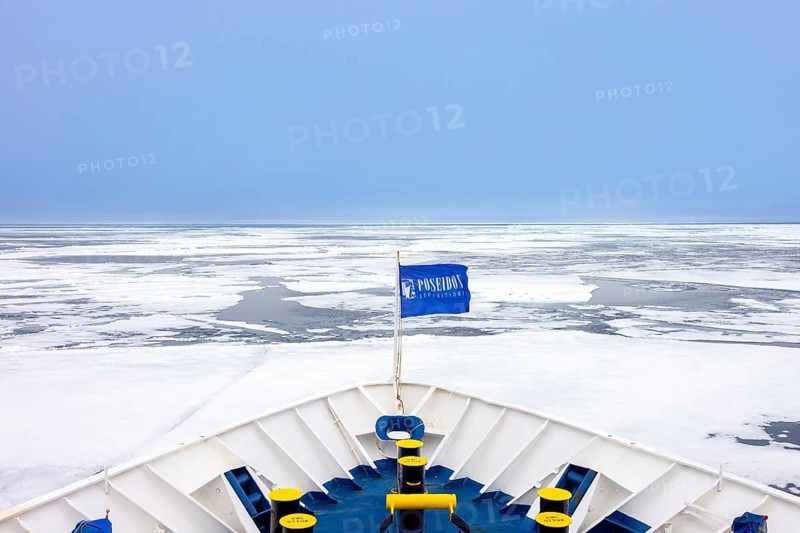 Drift ice, brash ice consists of ice floes and bow of Poseidon Expeditions cruise ship during Svalbard, Spitsbergen polar expedition in summer