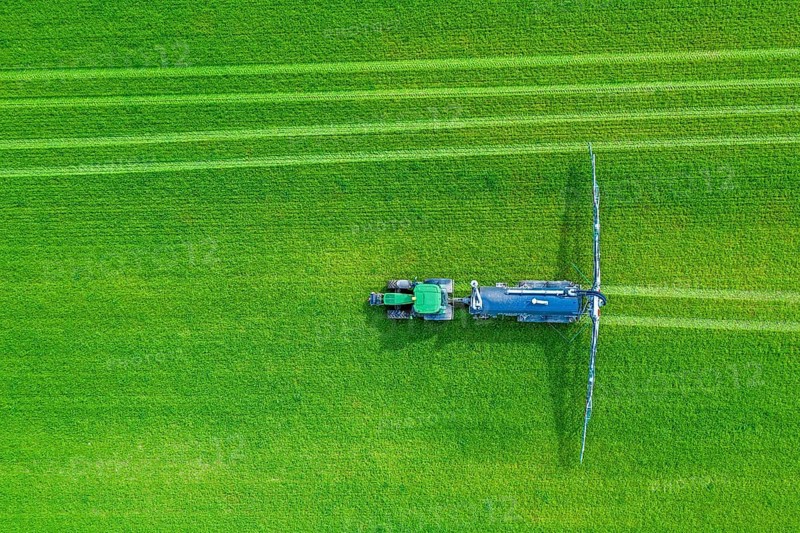 Aerial view over tractor towed liquid manure spreader, slurry spreader enabling the fertilization of arable land by distributing slurry in spring