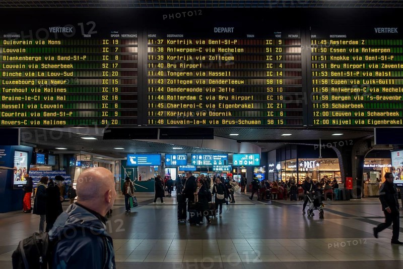 Commuter, tourist looking at train departures in departure hall of the NMBS Brussels-South railway station, Gare de Bruxelles-Midi, Belgium