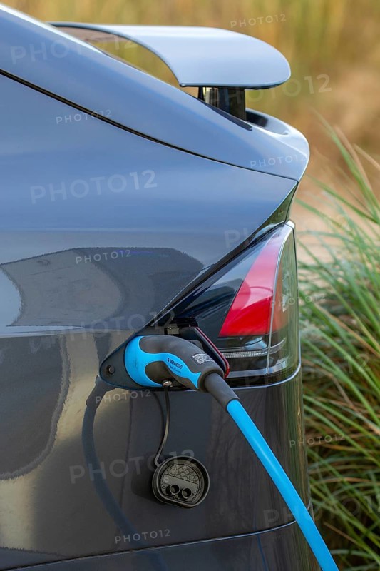 Close-up of electric vehicle / EV recharging at public charging station / loading point for electric cars showing cable, connector and vehicle inlet