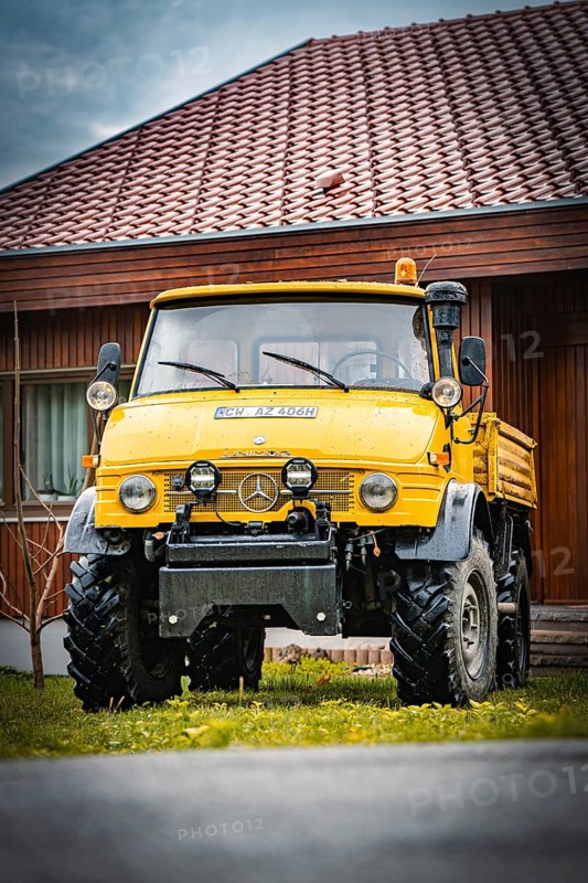 Yellow Unimog with four-wheel drive on a lawn in front of a wooden house, tree work, Gechingen, Calw district, Germany
