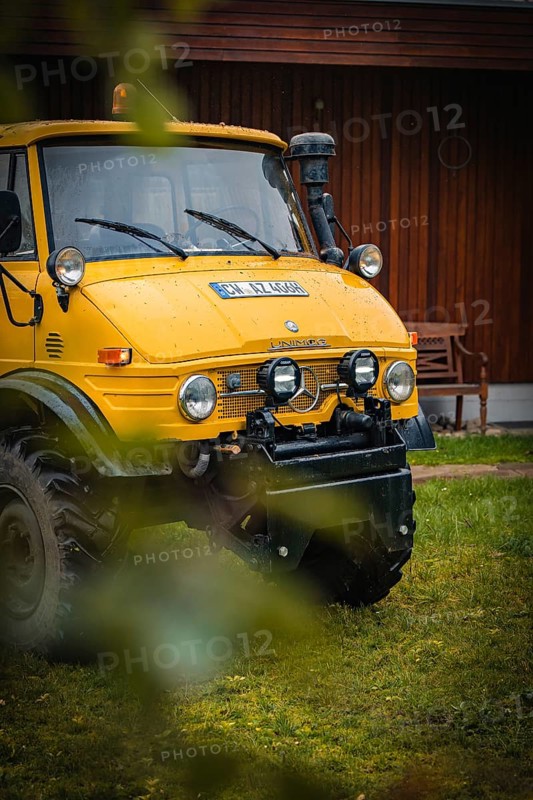 Yellow Unimog in the rain next to a wooden building in a meadow, tree work, Gechingen, Calw district, Germany