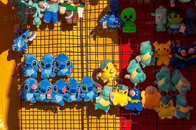 Close-up of blue, yellow and green plush prize dolls at game kiosk at Fun Show traveling ride park, Old Port of Montreal, Quebec, Canada