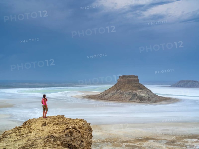 A tourist admires the inselbergs Karamaya and the Three Brothers (Three Batyrs), the Karagiye Depression with its salt lake (Kendirli Sor) on the ancient Tethys Ocean floor, Karyn Zharyk, Ustyurt Reserve, Mangystau, Kazakhstan, Asia