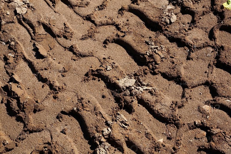 Close-up and top view of deep tire tracks made by earth loader in light brown sand at construction site, Quebec, Canada