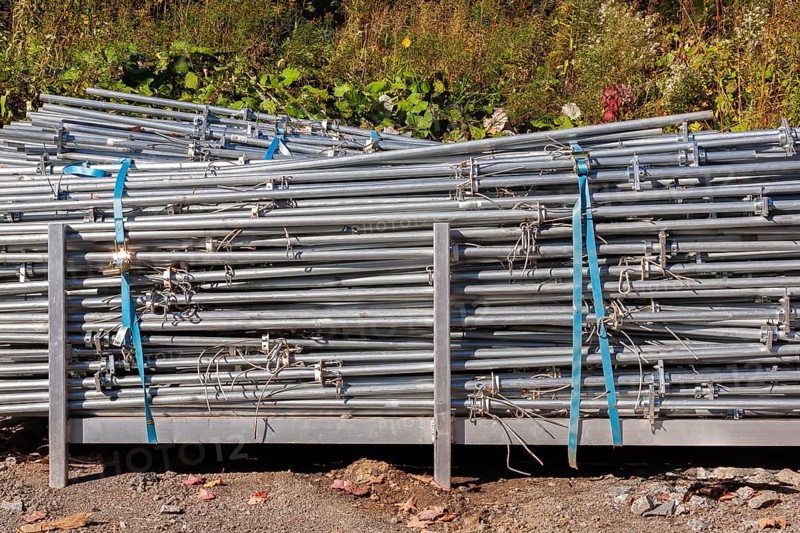 Pile of stacked heavy duty galvanized steel poles in outdoor storage yard in early autumn, Quebec, Canada