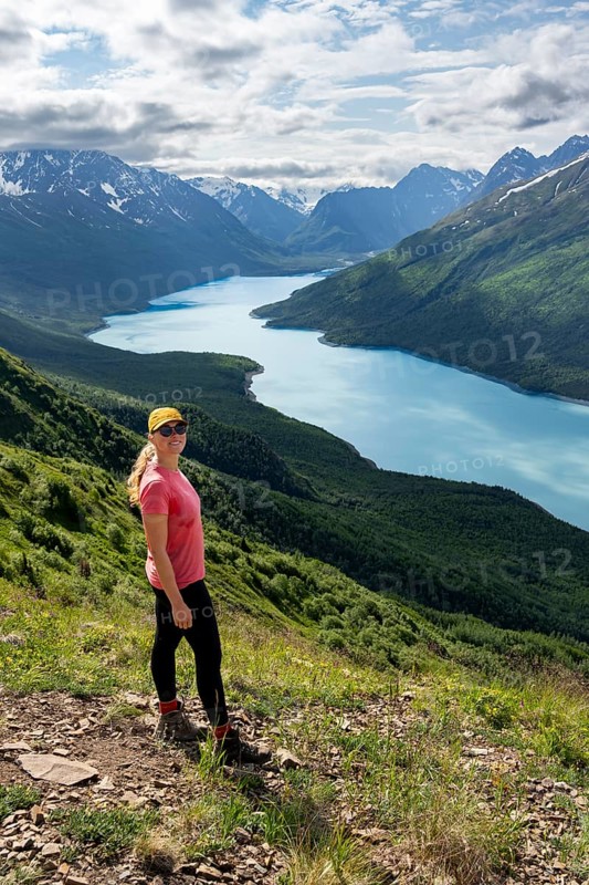 Female mountaineer enjoying views of blue lake and mountains on Twin Peaks Trail, Eklutna Lake, Chugach Mountains, Chugach State Park, Alaska, USA