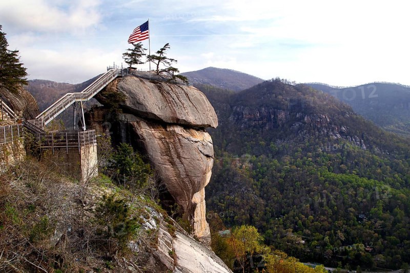 Chimney Rock with American flag and panoramic views of the forested mountains, zero