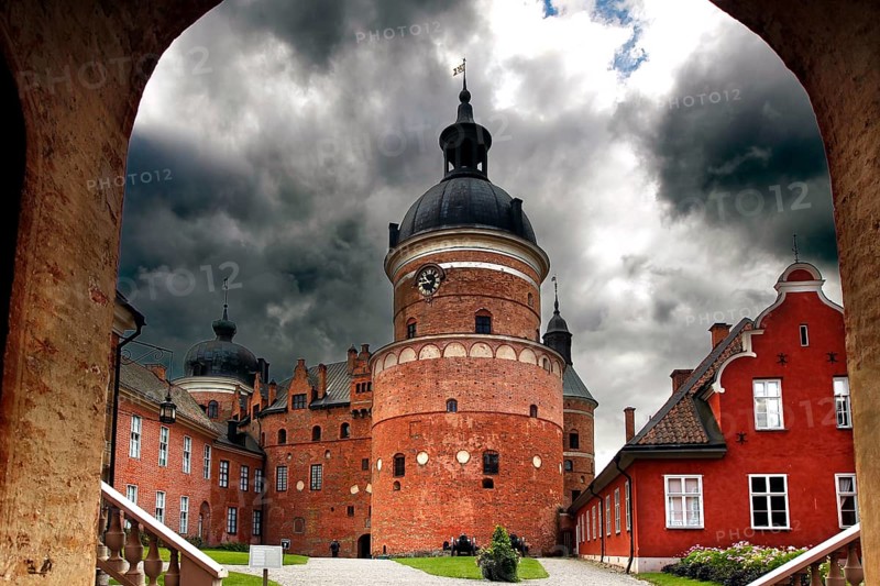 Gripsholm Castle in Mariefred through an archway with a heavily cloudy sky, Mariefred, Södermanland, Sweden
