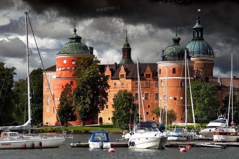 Gripsholm Castle in Mariefred against a cloudy sky with adjacent boats, Mariefred, Södermanland, Sweden