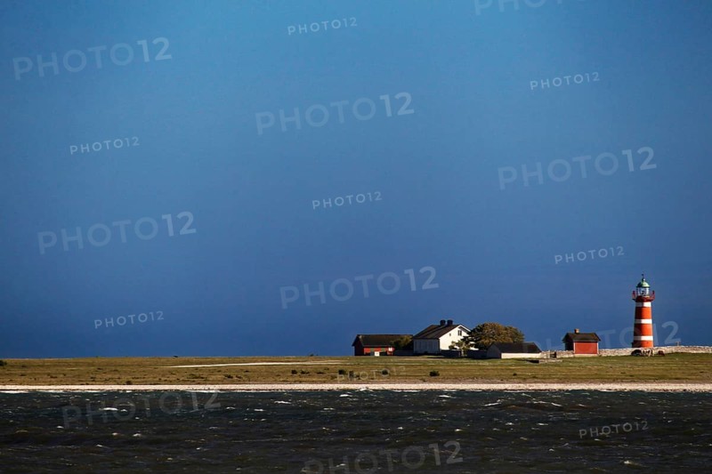 Lonely lighthouse on a quiet coastline under blue sky, Närsholmen, Gotland, Sweden