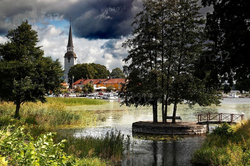 Atmospheric landscape with lakeside church surrounded by trees and clouds, Mariefred, Södermanland, Sweden