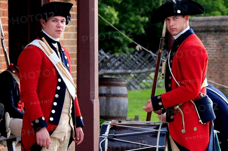 Two soldiers in red historic uniforms stand in front of a building and look alert, Williamsburg, Virginia, USA
