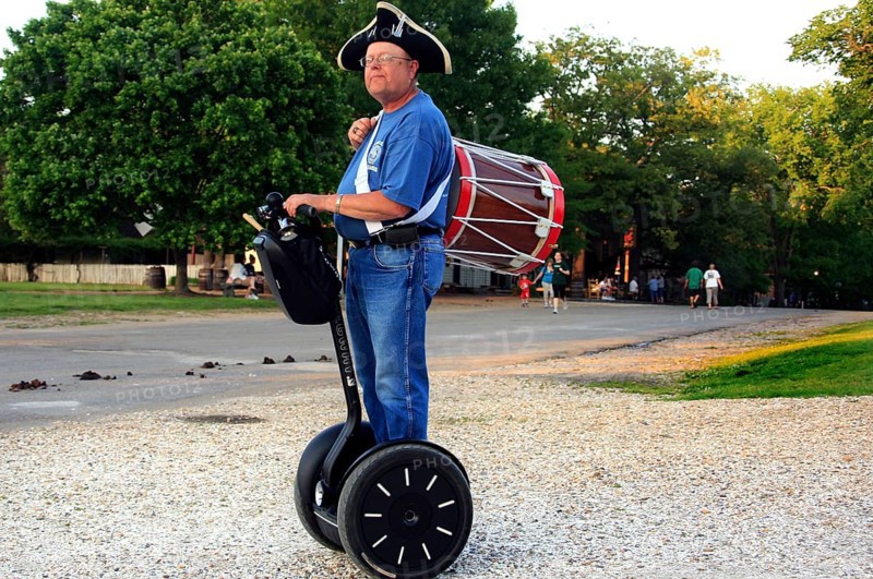 Man in period clothing rides on Segway and carries a drum, a rare sight, Williamsburg, Virginia, USA
