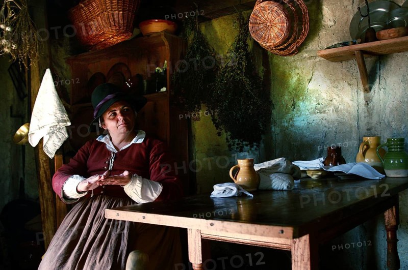 Woman wearing historical costume in a rustic house at Plimoth Plantation, Plymouth, Massachusetts, USA