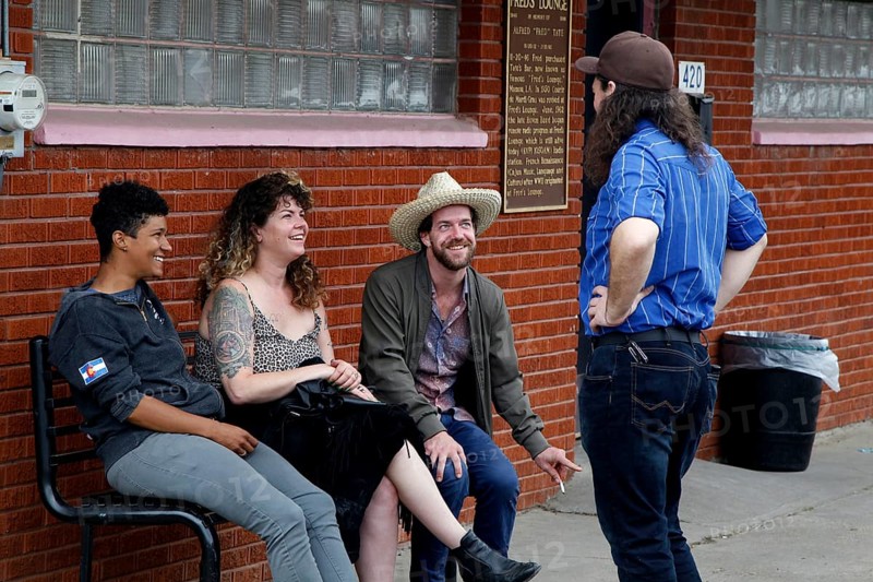 Four people sit relaxed in front of Fred's Lounge and laugh together, Mamou, Louisiana, USA