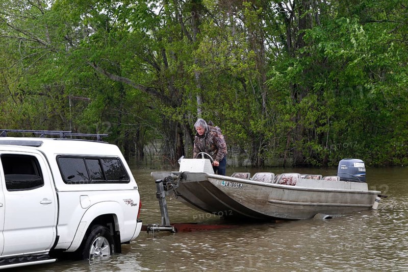 A pickup truck pulls a boat into the water at the Atchafalaya Basin, surrounded by dense forest, zero