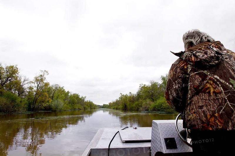 Person in a boat traveling on a calm river through a swamp, Atchafalaya Basin, Louisiana, USA