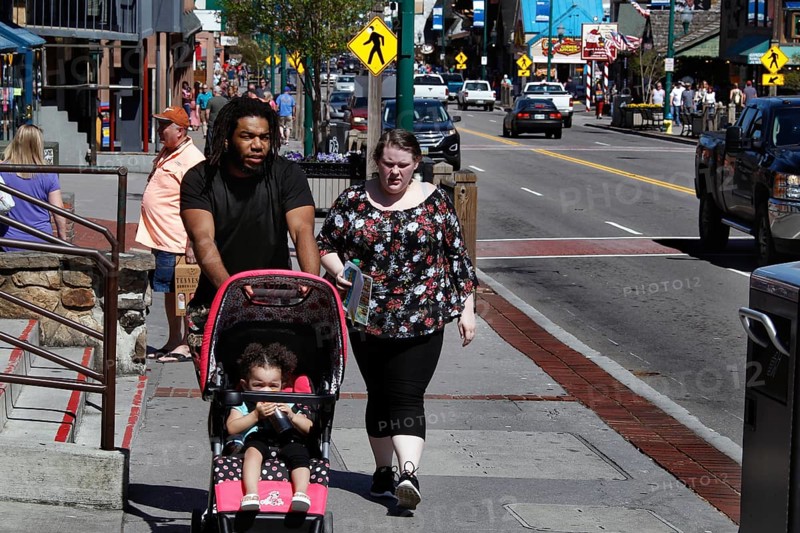 Family with stroller walking down the sunny main street of Gatlinburg, Gatlinburg, Tennessee, USA