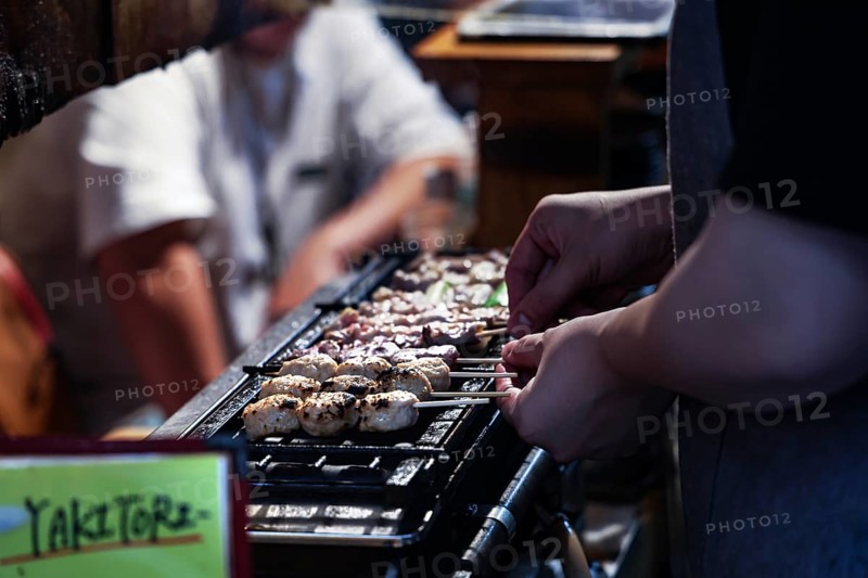 Grilling yakitori skewers in a busy bar setting, Shinjuku, Tokyo, Japan