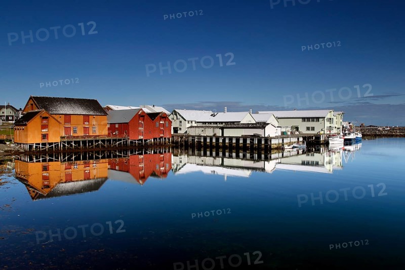 Warehouses in Vardø harbour are reflected in still water, Vardø, Finnmark, Norway