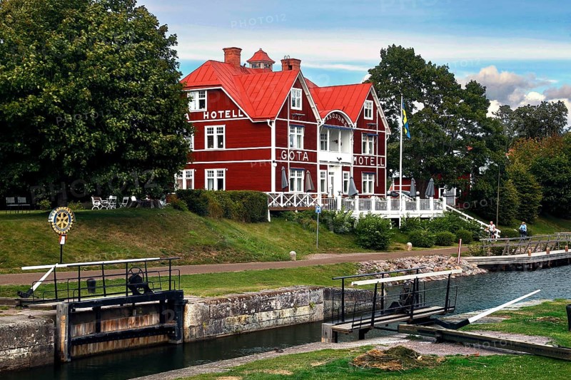 Red Göta Hotel in Borensberg on the Göta Canal next to a lock, surrounded by green trees, Borensberg, Sweden