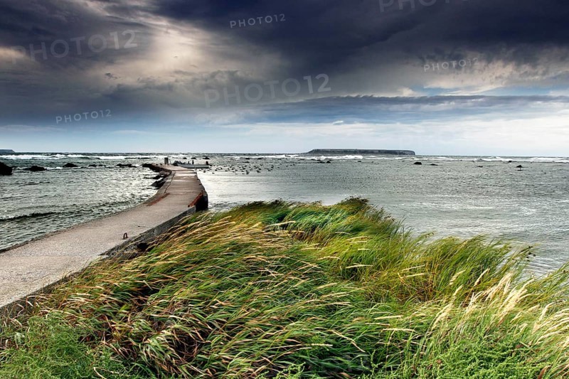 Stormy coastal landscape with jetty, dark clouds and wild sea, Gotland, Sweden