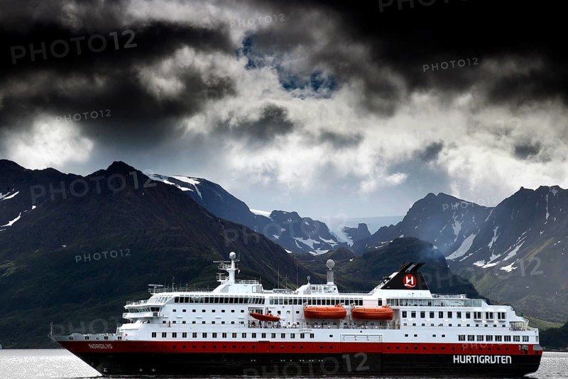 Hurtigruten ship under impressive dark clouds and mountainous landscape, Øksfjord, Norway