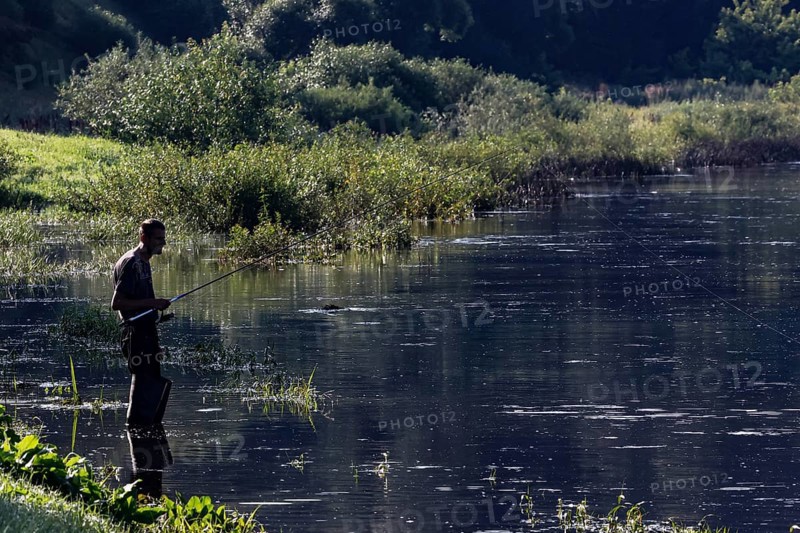 An angler stands patiently on the banks of the Nemunas River in Vilkija, Vilkija, Lithuania