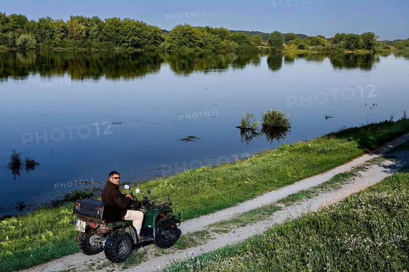 Person rides ATV on a path along the Nemunas River near Vilkija, Vilkija, Lithuania