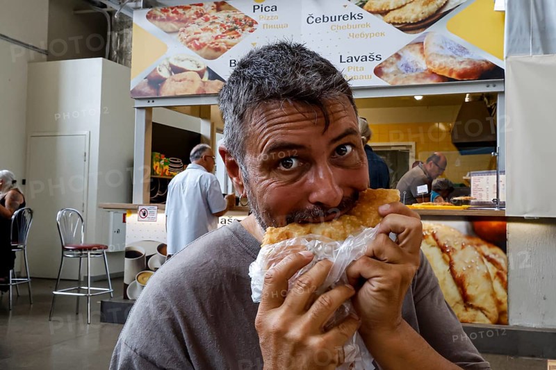 Man enjoying cheburek in the lively Central Market of Riga, Riga, Latvia