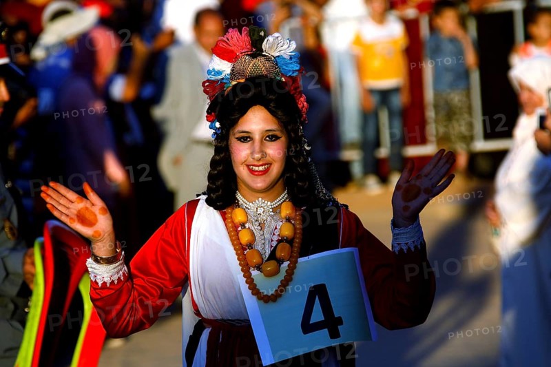 Smiling woman in traditional dress taking part in the Fête des Roses, El Kelâa m'Gouna, Marrakesh-Safi, Morocco