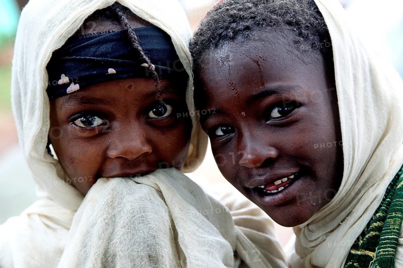 Two children wearing traditional clothes smile during a church service