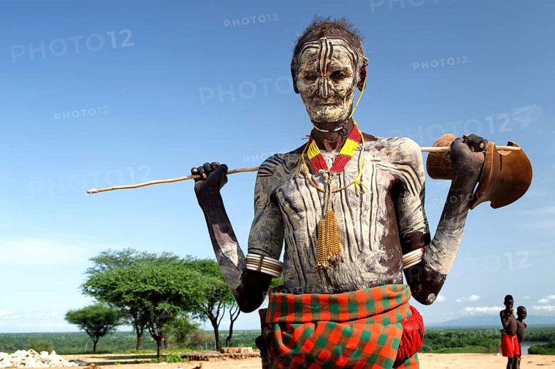 Old man from Murle with traditional checkered painting and antelope head, Murle, Ethiopia