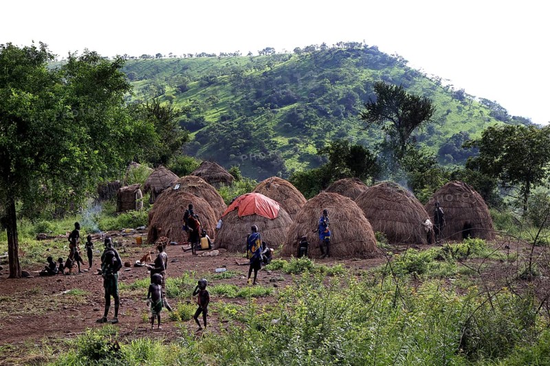 Several Morsi huts in a green valley with mountains in the background, Mago National Park, null, Ethiopia