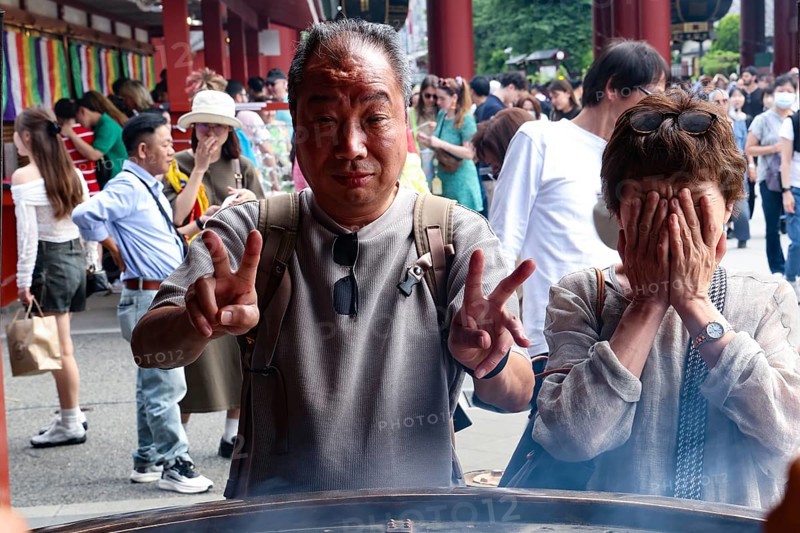Visitors to Senso-ji Temple pose in front of a large fire bowl, Tokyo, Japan