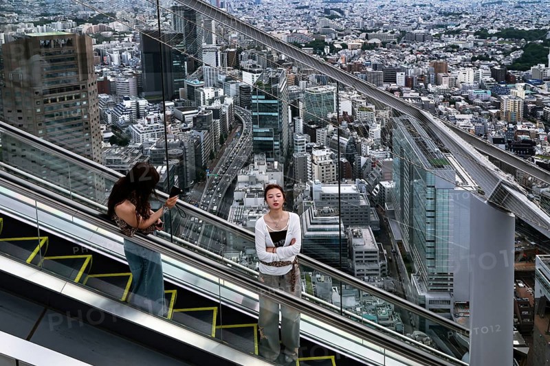 Women ride the escalator in Shibuya with sweeping views over Tokyo, Tokyo, Japan